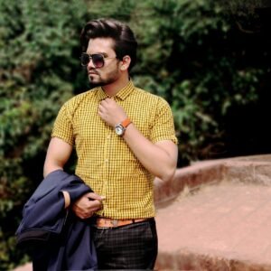 Stylish man wearing sunglasses and checkered shirt posing outdoors in Mahabaleshwar.